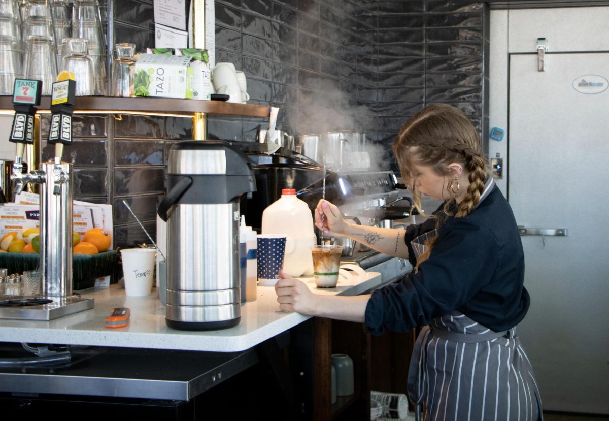 A barista at Parkside Station makes a coffee beverage for a customer. The restaurant recently opened and offers a full service restaurant and bar with a pastry and coffee counter.