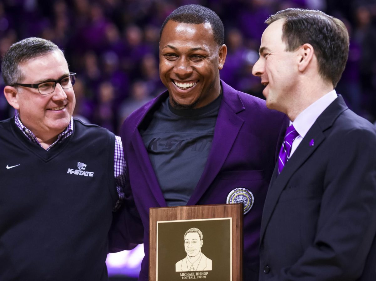 Michael Bishop, K-State quarterback from 1997-98 — during which he led the Wildcats to their first No. 1 ranking and first Big 12 North Title and almost to the national championship and was a runner-up for the Heisman Trophy — smiles as he is honored for being inducted into the K-State Athletics Hall of Fame by K-State President Kirk Schulz (left) and Athletic Director John Currie (right) at halftime of the men's basketball game against Ole Miss on Jan. 30, 2016, in Bramalge Coliseum.