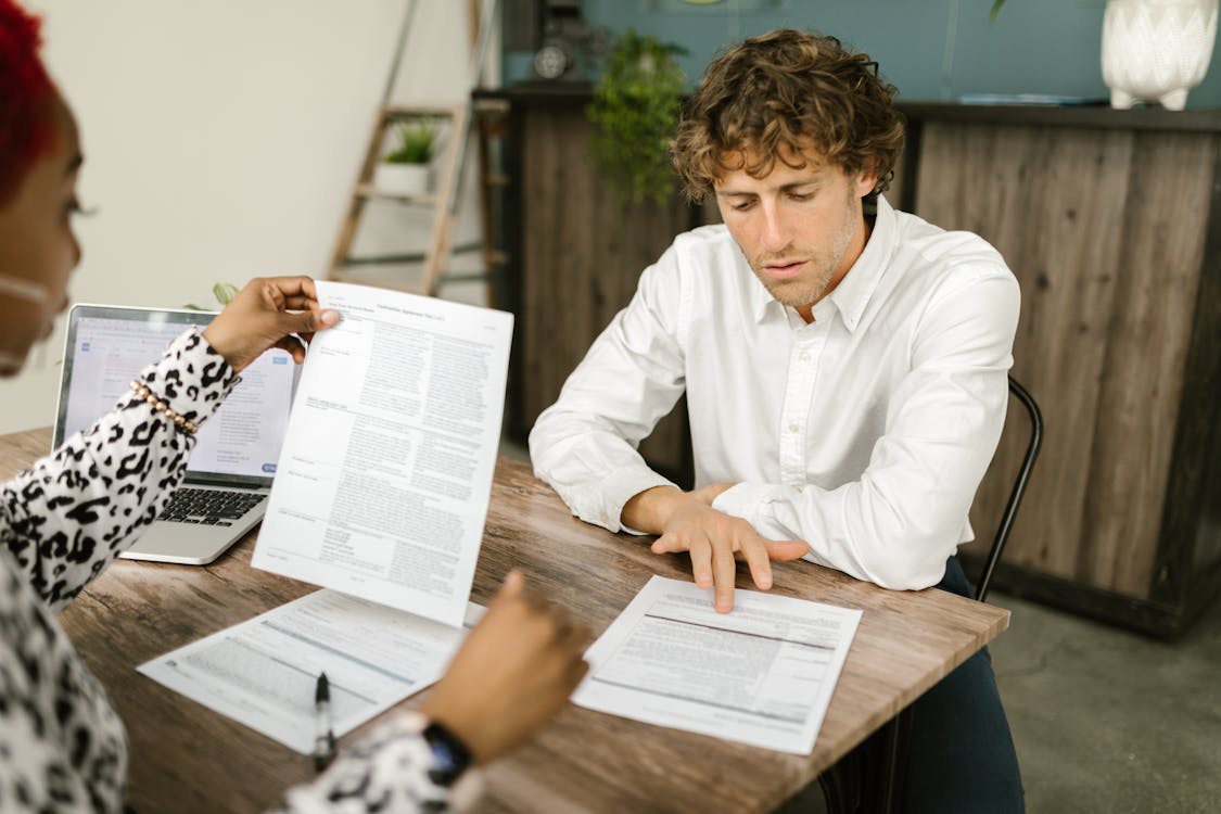 Free Two professionals reviewing documents in an office setting, focused on analytical tasks. Stock Photo