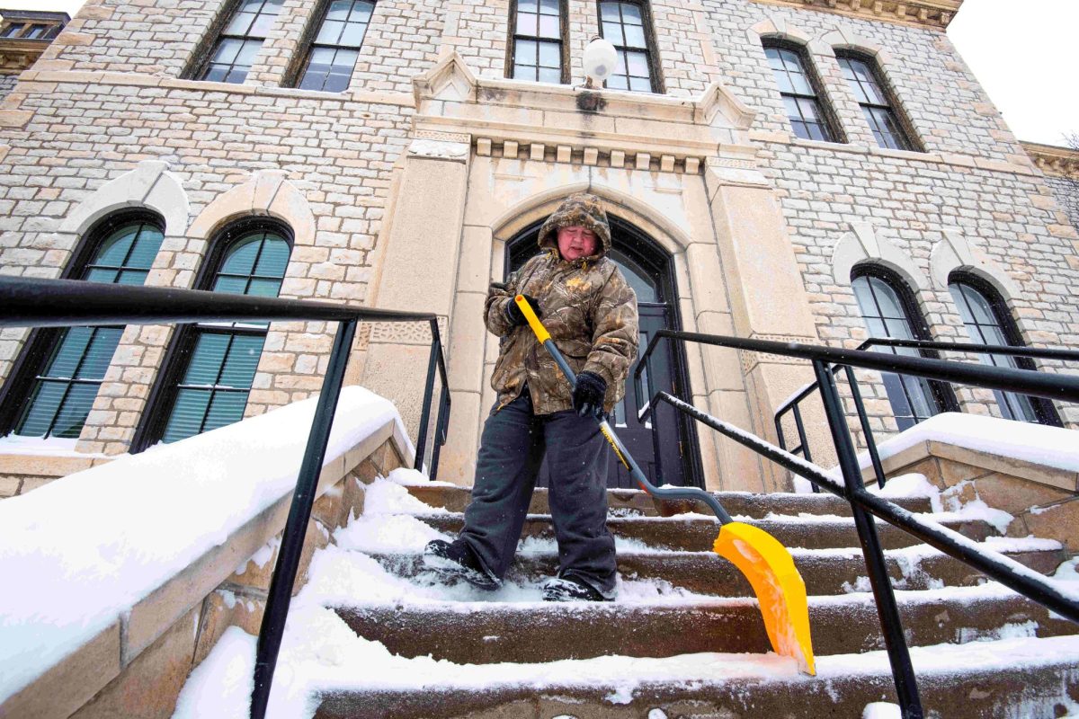 An employee for Kansas State Facilities clears the entrance steps to Fairchild Hall in the afternoon of Tuesday, Feb. 18. Employees arrived on campus at 5 a.m. Tuesday morning to begin clearing campus of the winter storm.