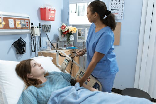 Free Nurse providing care to a patient in a hospital room with medical equipment. Stock Photo