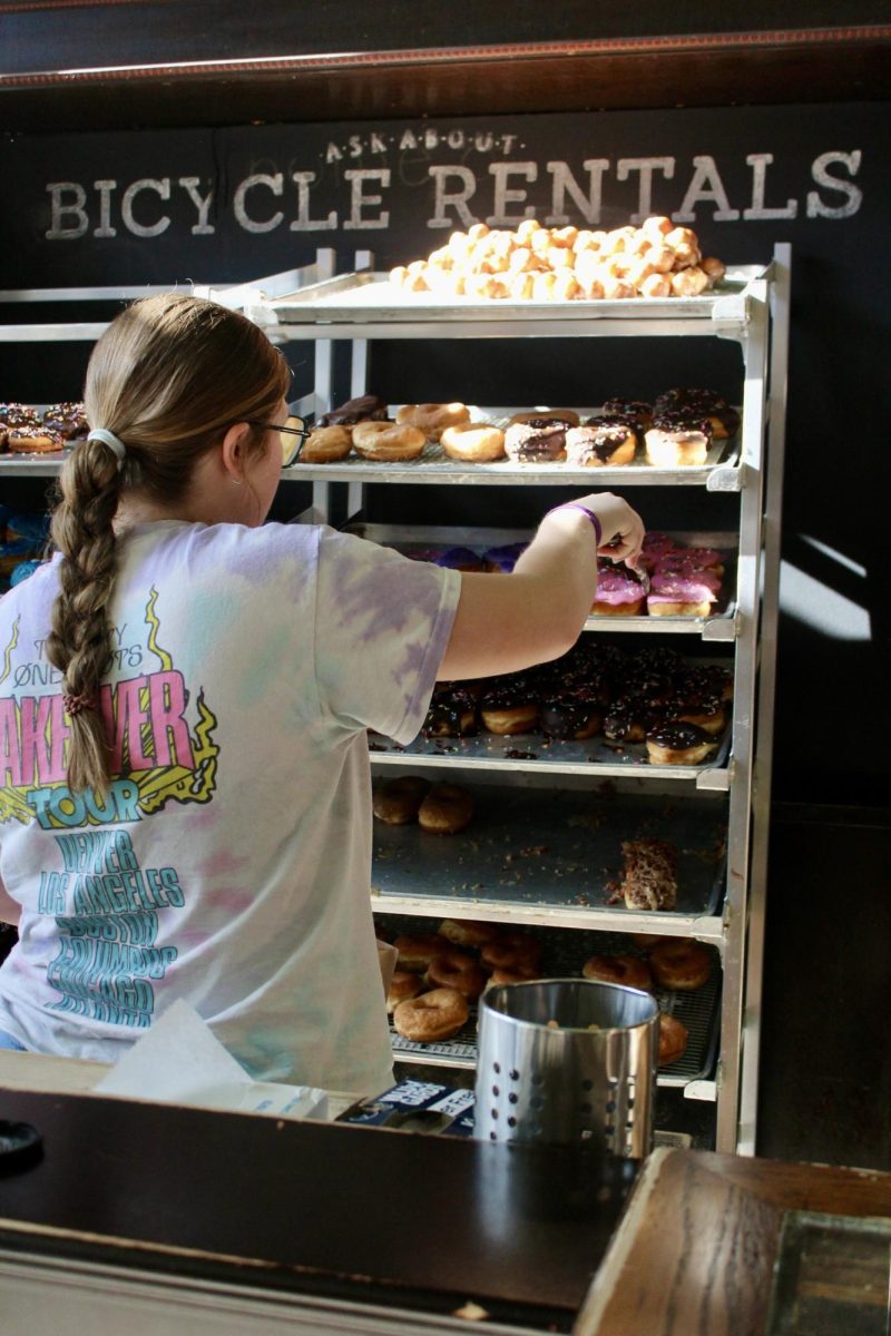 A student worker grabs donuts to serve to customers. 