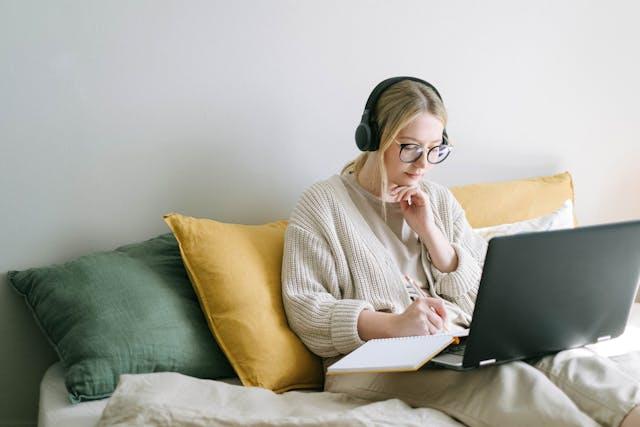 A person sitting on a bed with a computer and headphones

AI-generated content may be incorrect.