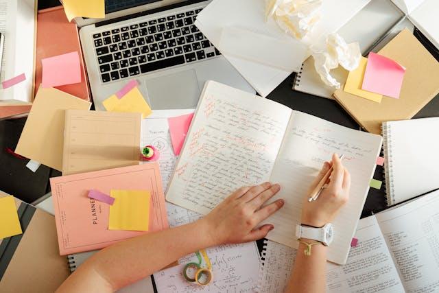 A person writing in a notebook AI-generated content may be incorrect.