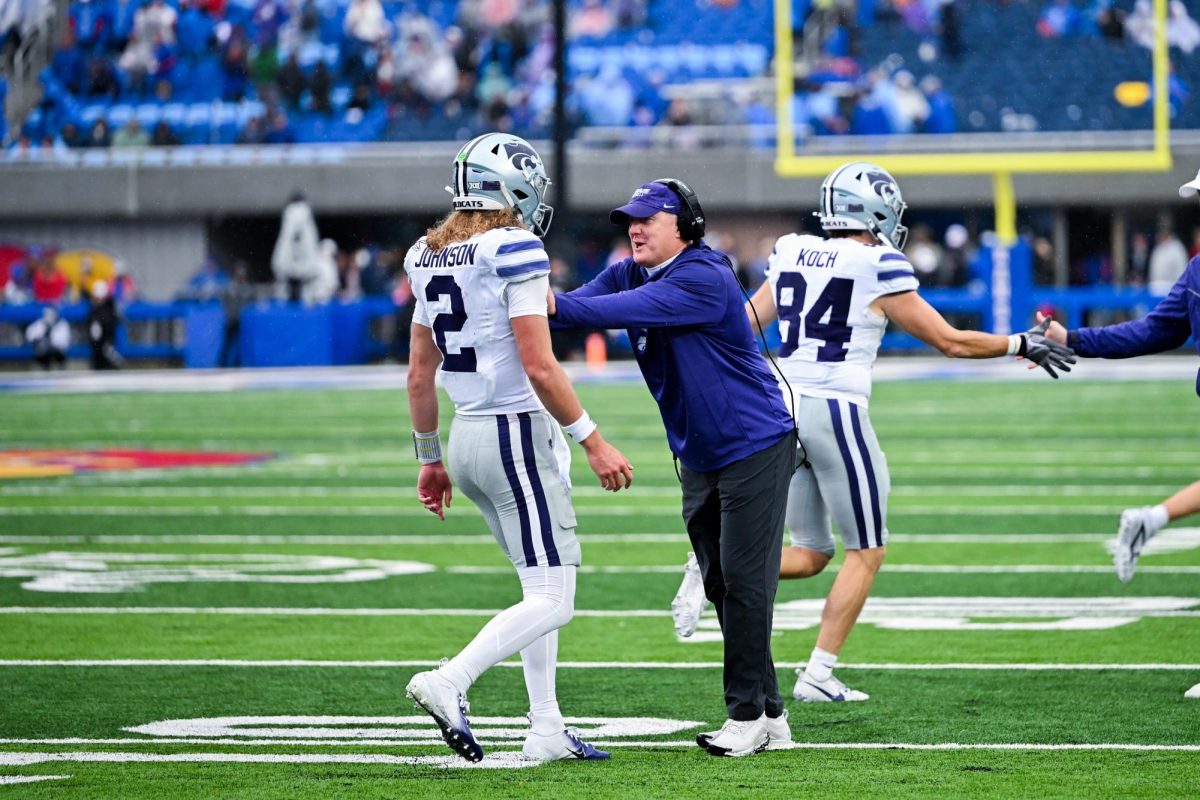 Quarterback Avery Johnson is met on the sideline by the Wildcats’ head coach during the Sunflower Showdown in Lawrence. The two share a moment of energy and encouragement as K-State kept control throughout the rivalry matchup. The Wildcats went on to defeat Kansas 42–17, marking their 17th straight win over the Jayhawks in the series.