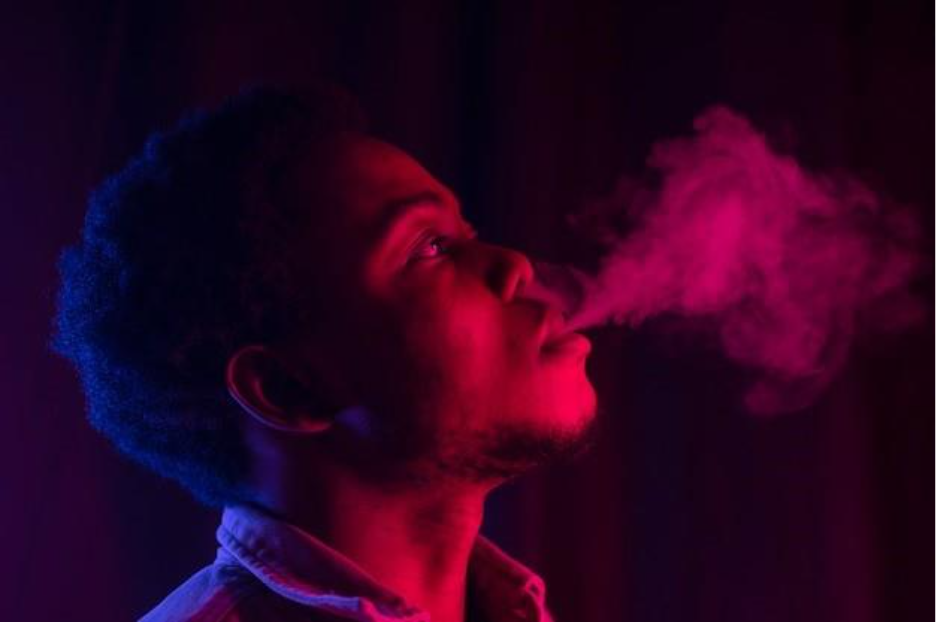 man vaping from a hookah indoors