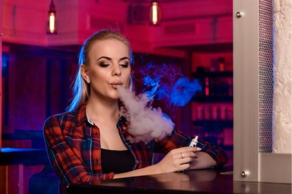 young pretty woman in a shirt in a cage smoke an electronic cigarette at the vape bar. vape shop.