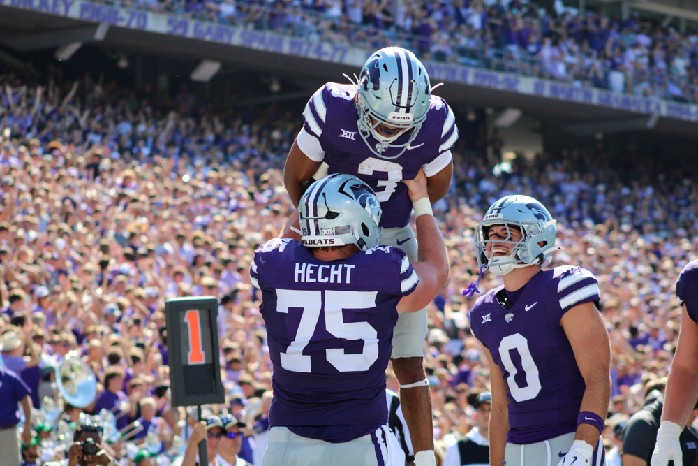 Hecht (75) lifts Dylan Edwards (3) in celebration after Edwards scores a rushing touchdown, while Maddox Schulte (0) smiles and laughs nearby, congratulating him on the accomplishment during K-State’s game on September 27. 