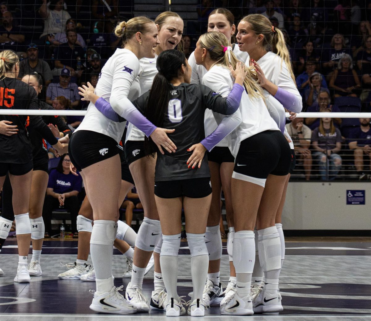 Kansas State volleyball players huddle together after scoring a point during the Wildcats’ match on Aug. 30, at Morgan Family Arena in Manhattan.