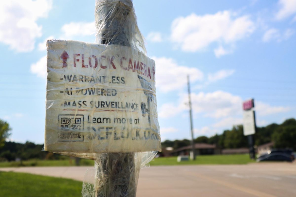 A closer look at the sign posted under the Flock camera near South Seth Child Road. The sign states that Flock cameras are "warrantless," "AI powered" and contribute to "mass surveillance." The sign provides a QR code to DeFlock.org where people can learn more about Flock cameras and locate ones in their area. This is one of 11 Flock cameras that the Riley County Police Department operates in Manhattan.