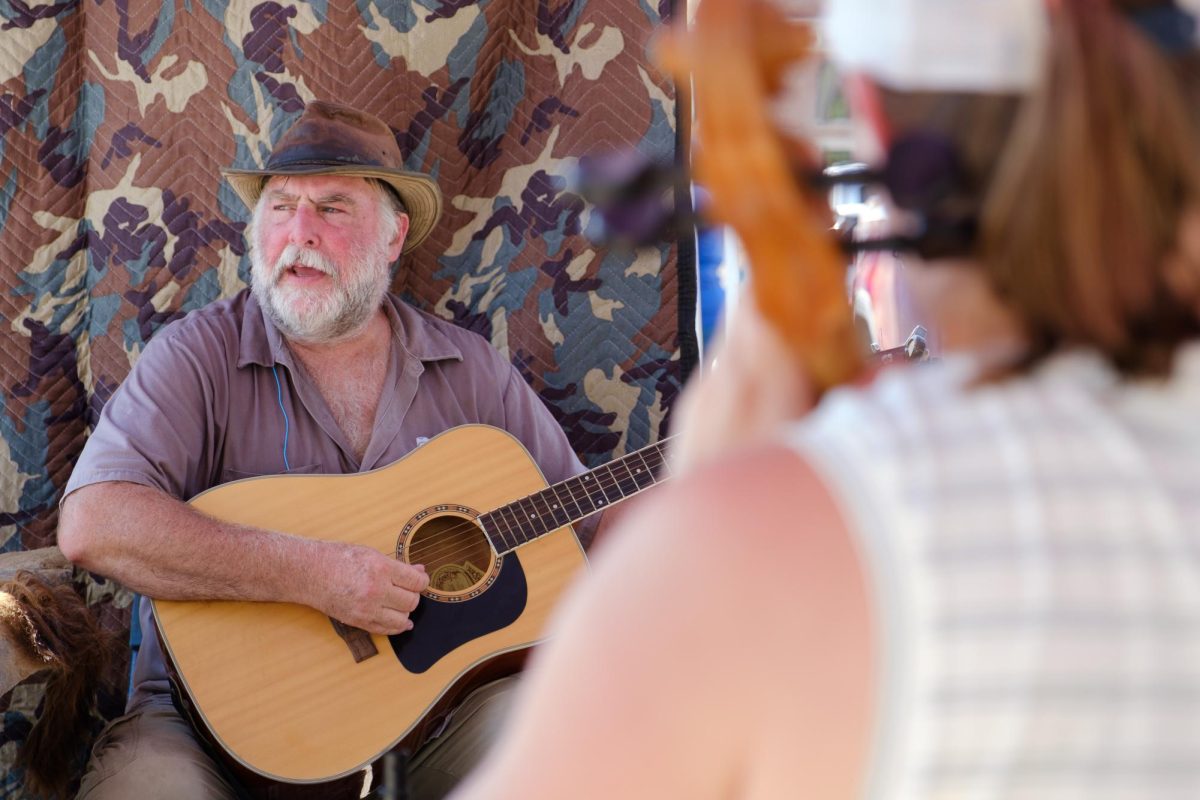 George LeRoux, owner of Flint Hills Prairie Bison Preserve, sings and plays guitar during an open jam session in his booth at the Manhattan Farmer's Market on Sept. 5. 